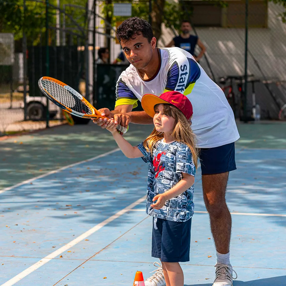 bambina impara a giocare a tennis con l'istruttore del villaggio