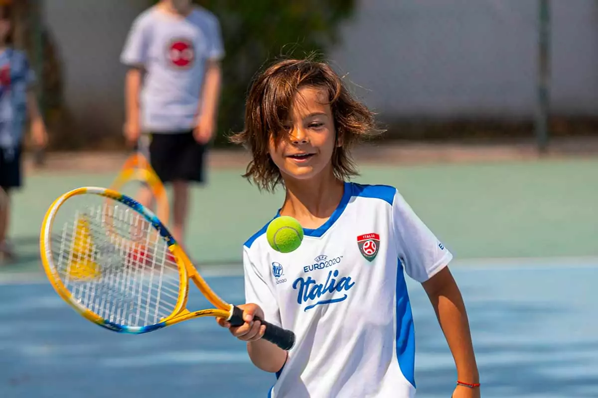 bambino che gioca a tennis al villaggio san francesco