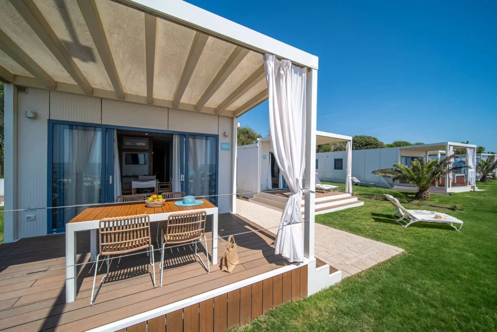 Veranda moderna con tavolo, sedie e prato verde.